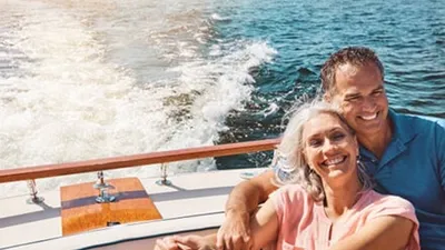 Smiling couple seated together on the back of a moving boat