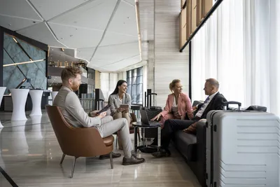 Four business travelers talking in a hotel lobby with luggage nearby