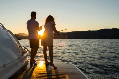 Couple fishing from the back of a boat at sunset