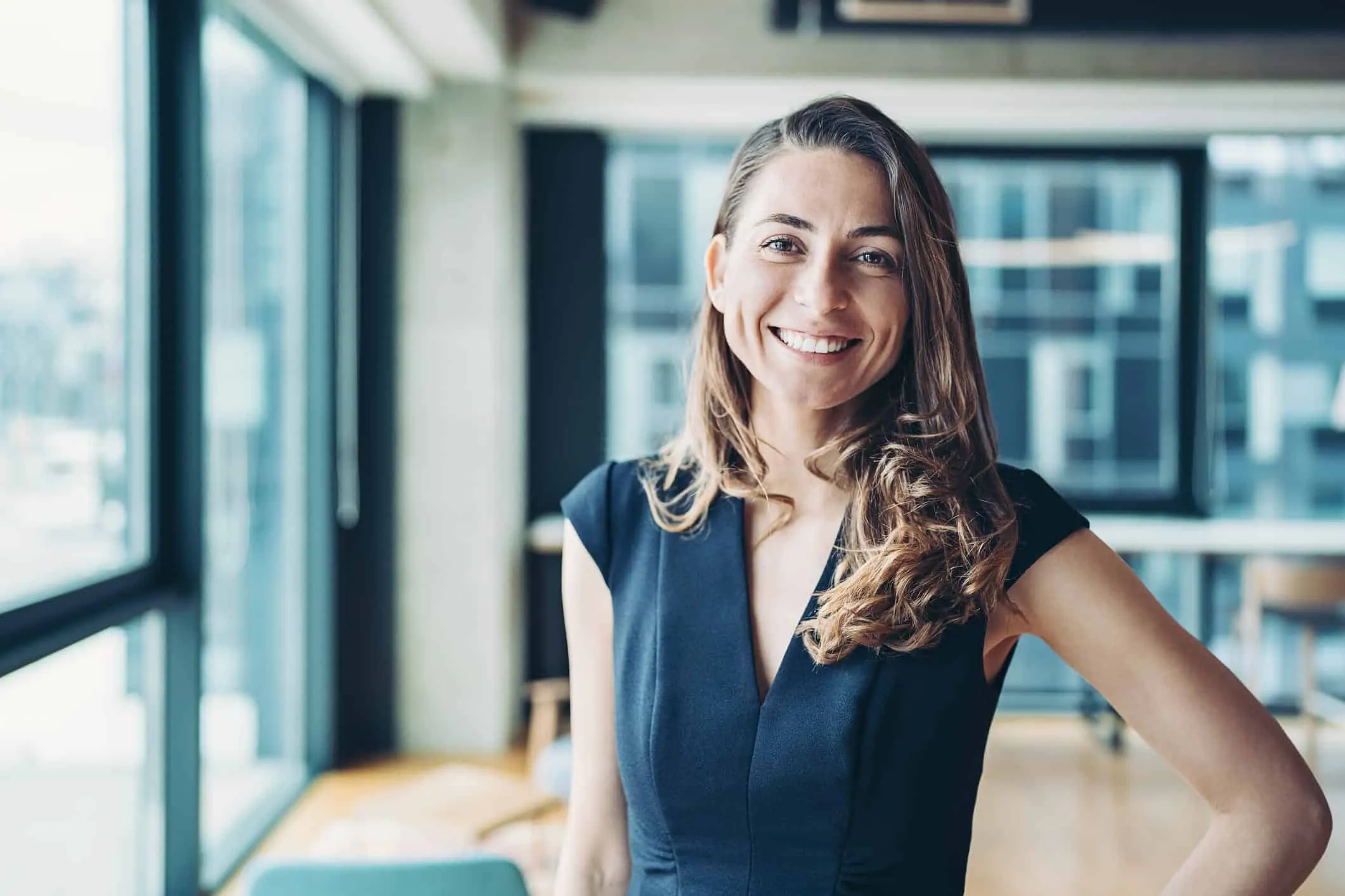 Smiling woman in a dark dress standing in a bright office