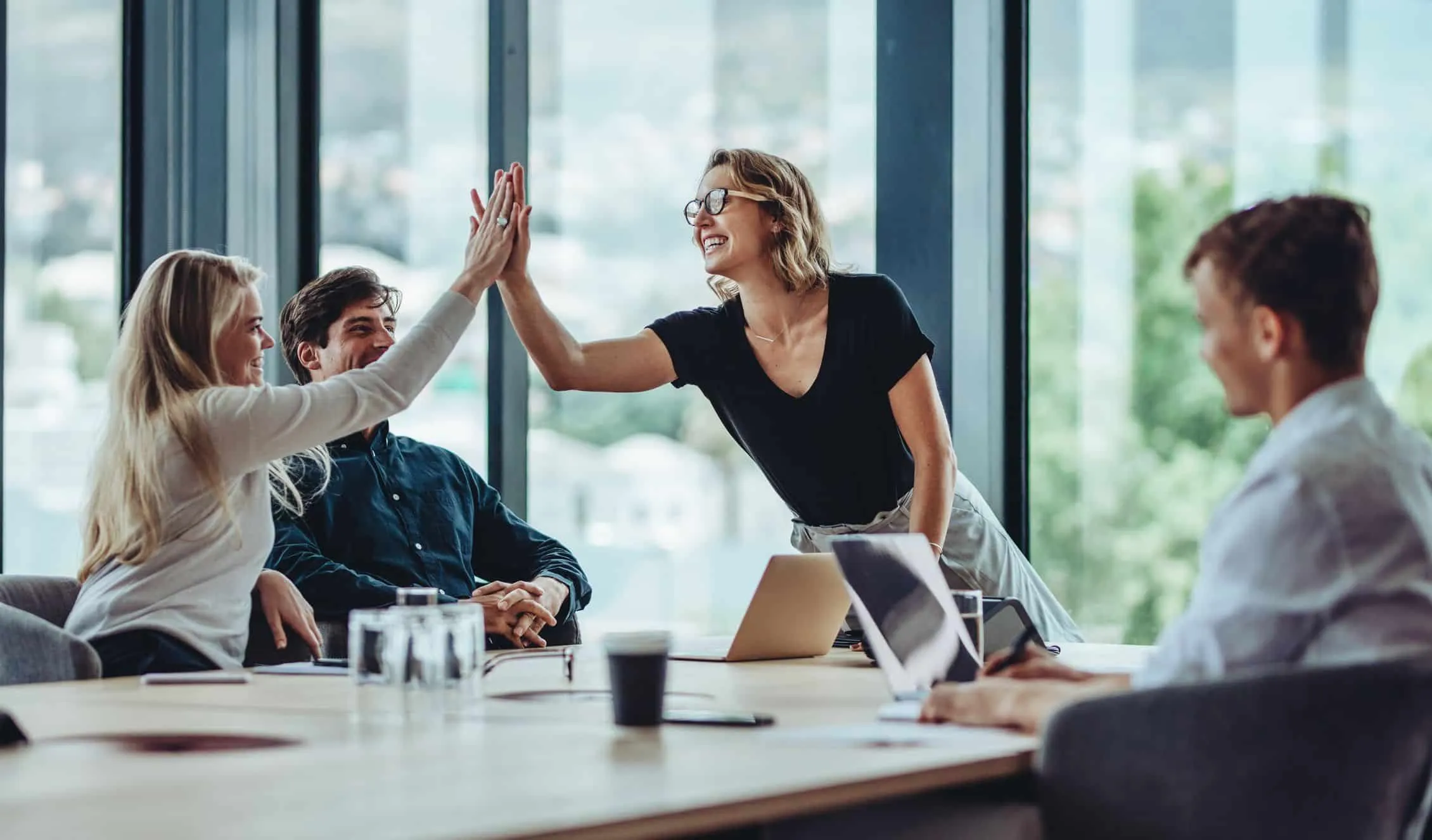 Coworkers exchanging a high five around an office meeting table