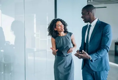 Man and woman in business attire talking in an office