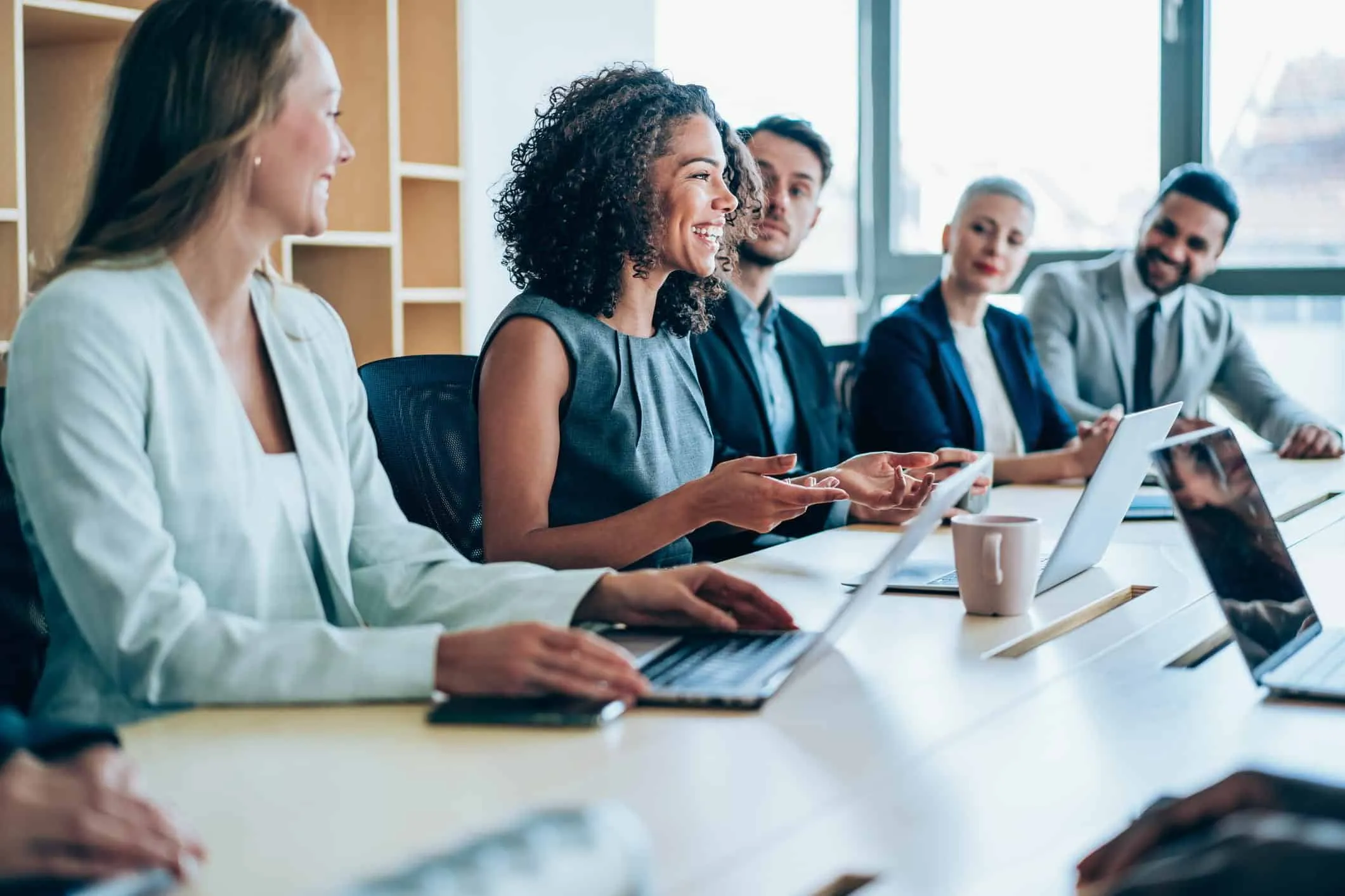 Group of colleagues with laptops talking around a conference table
