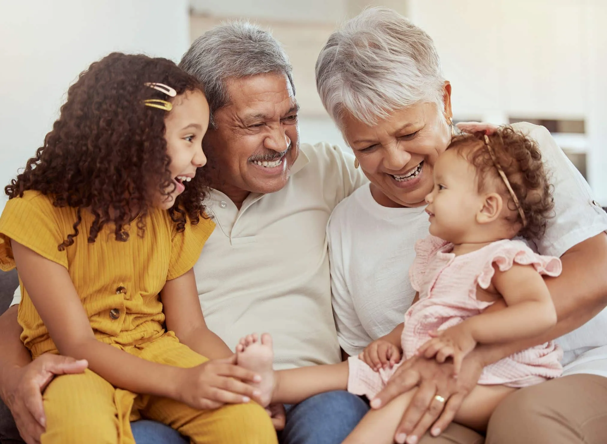 Grandparents on a sofa smiling with two young granddaughters