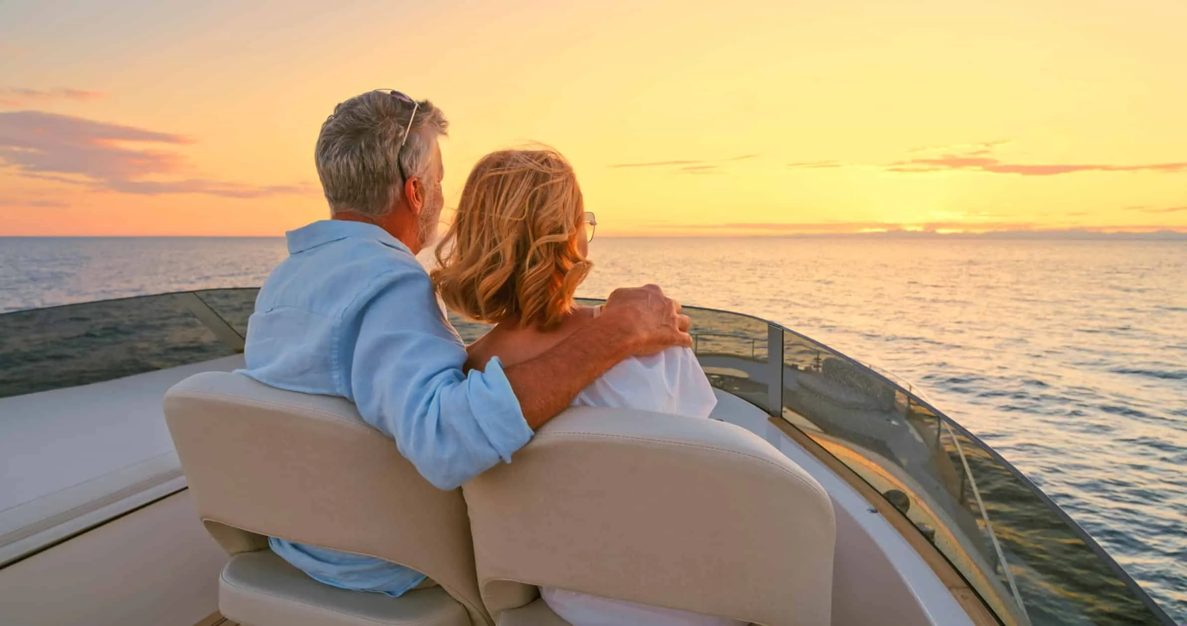 Older couple sitting together on the deck of a boat at sunset