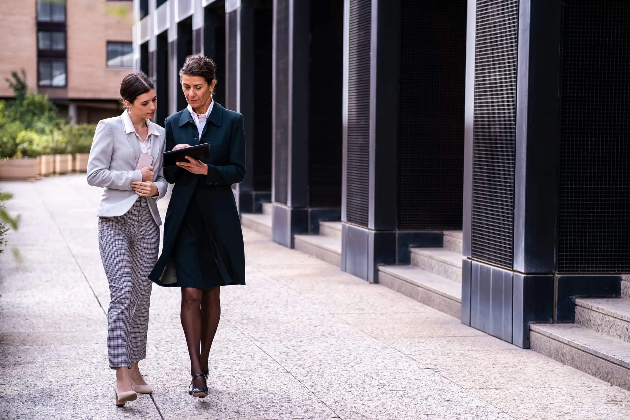 Two businesswomen walking and talking outside an office building