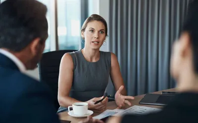 Woman speaking with colleagues across a meeting table