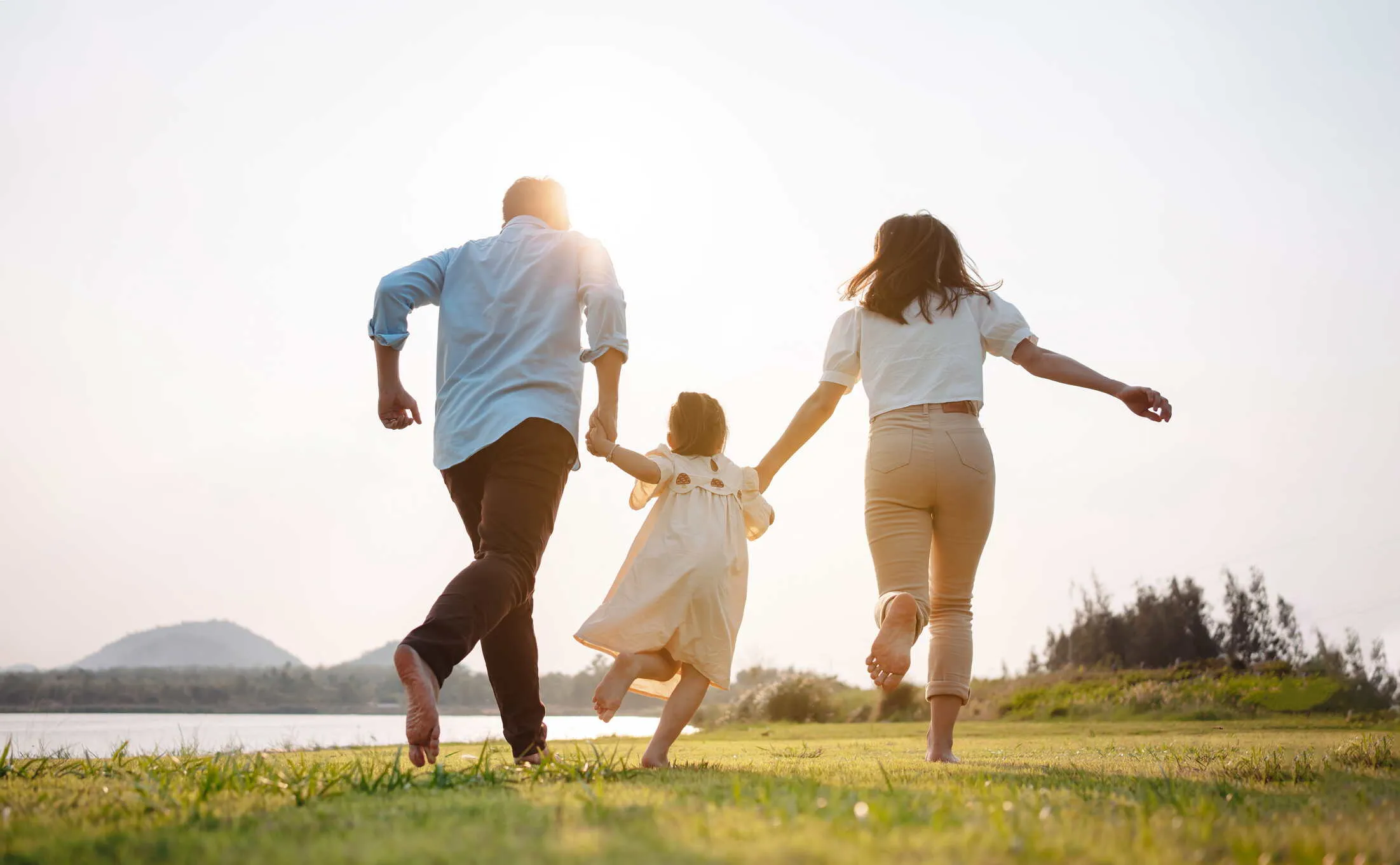 Family holding hands and running across a grassy field