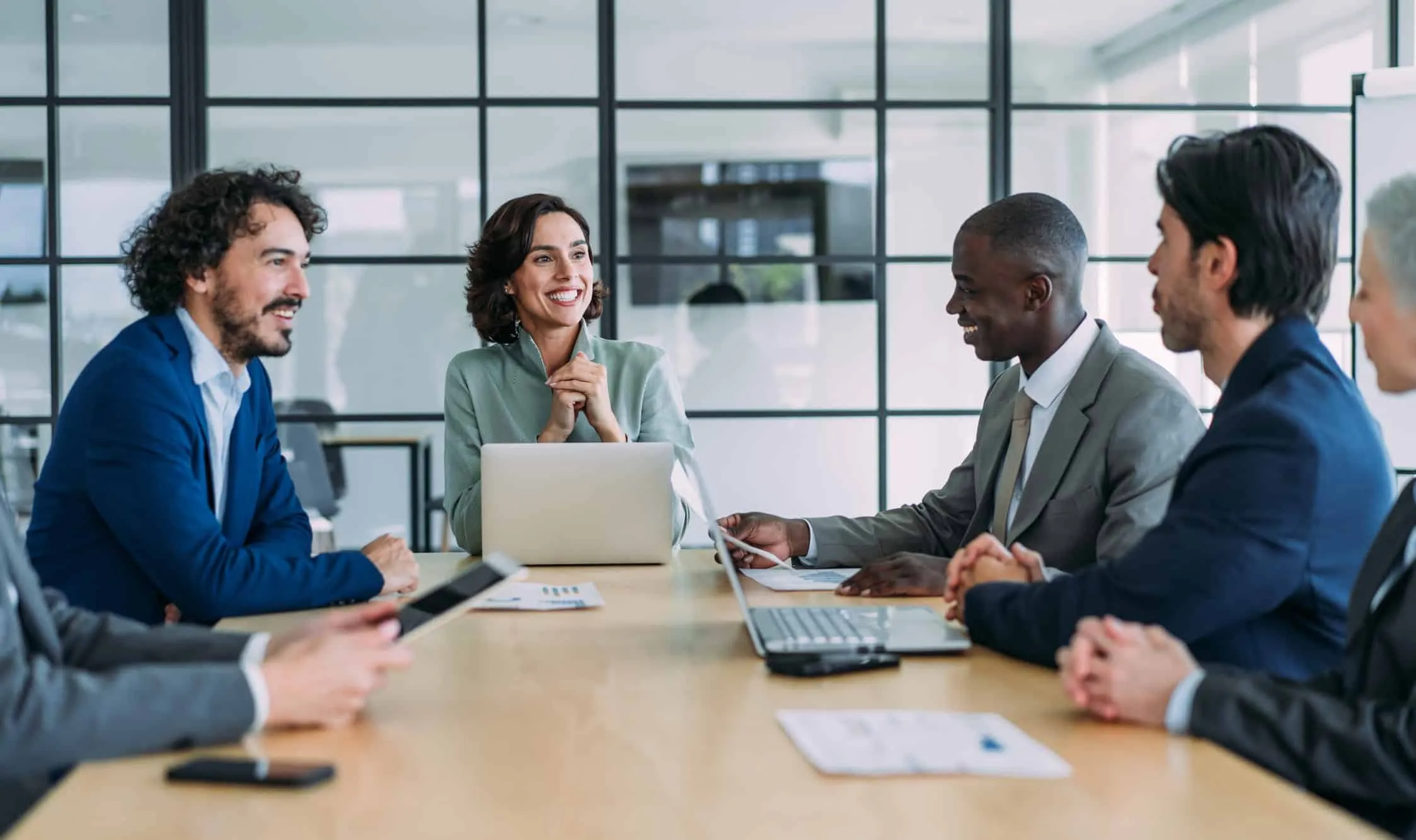 Colleagues talking around a conference table with laptops
