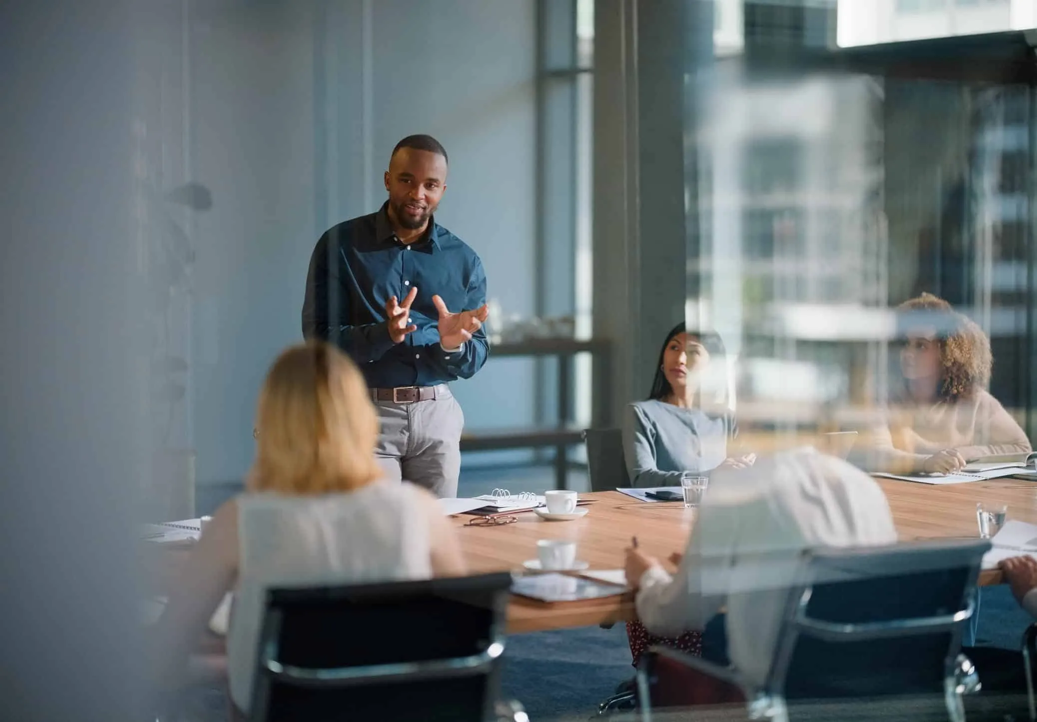 Man presenting to colleagues seated around a conference table