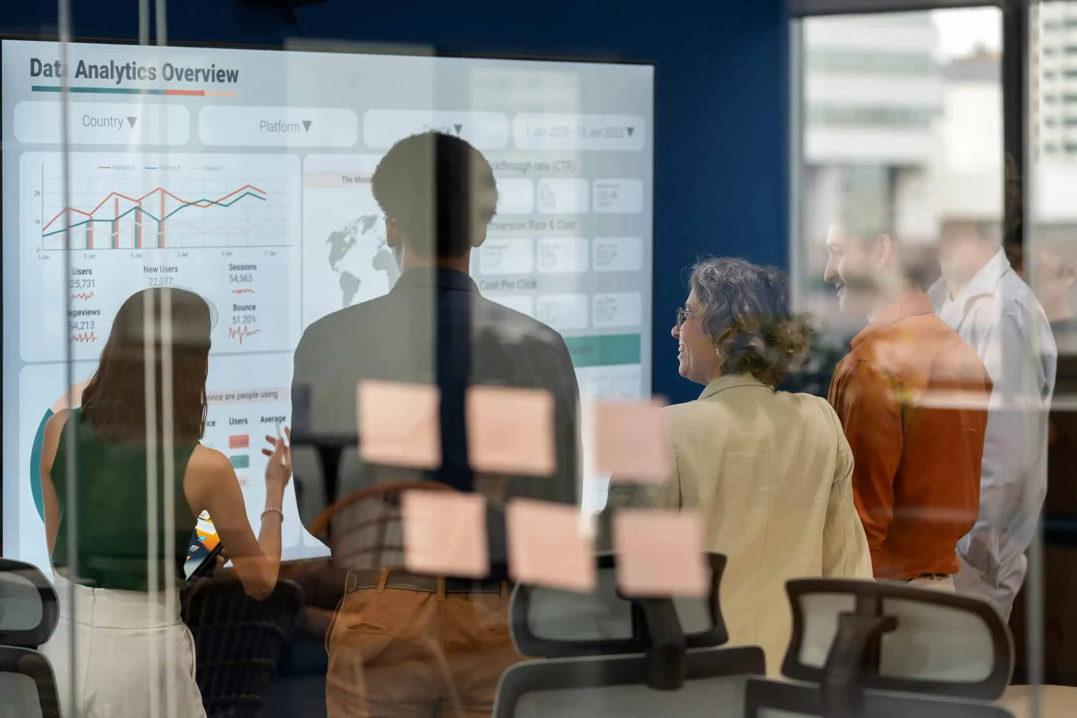 Colleagues reviewing charts on a large screen behind a glass wall