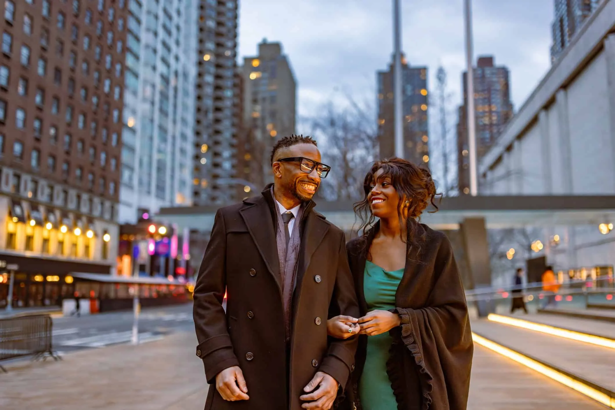 Couple walking arm in arm on a city street at dusk