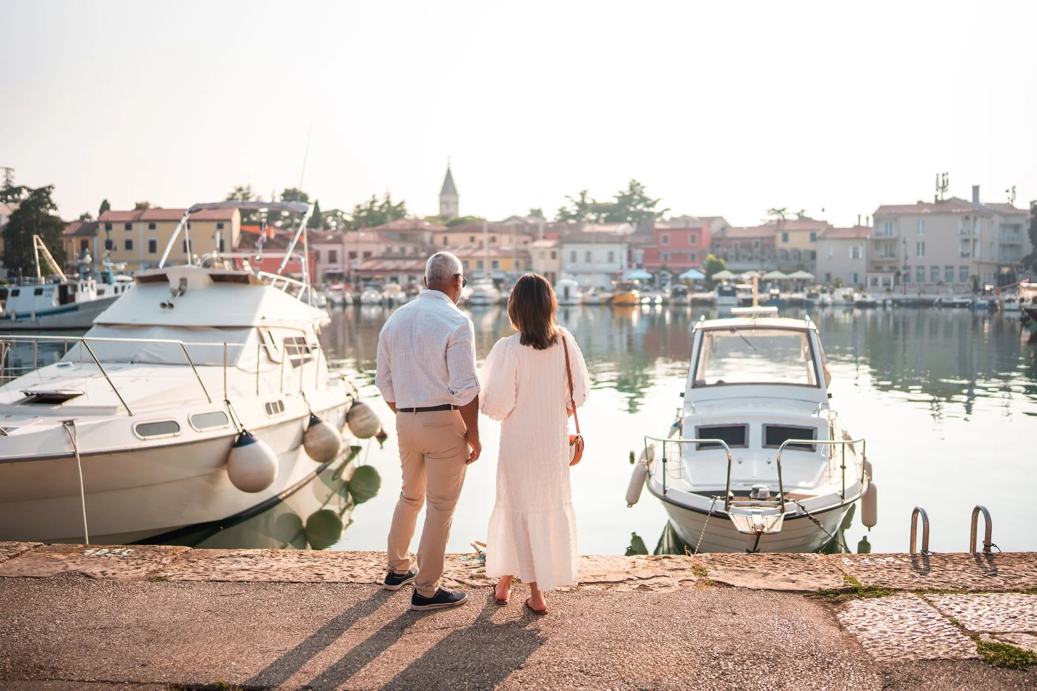 Couple standing on a harbor dock looking at moored boats