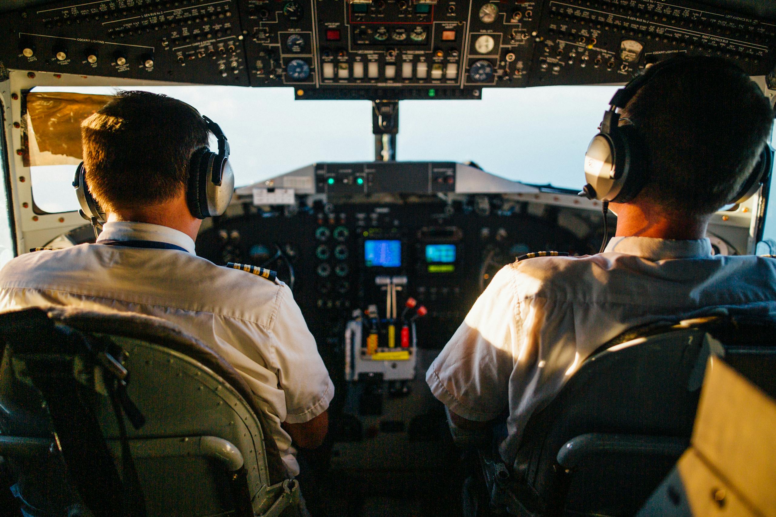 Two pilots in cockpit navigating airplane at high altitude, daylight